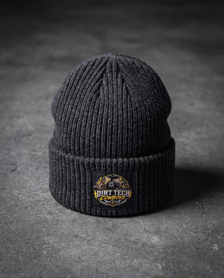 Charcoal heather Dirt Tech Cowboys cuffed knit beanie on dark concrete.