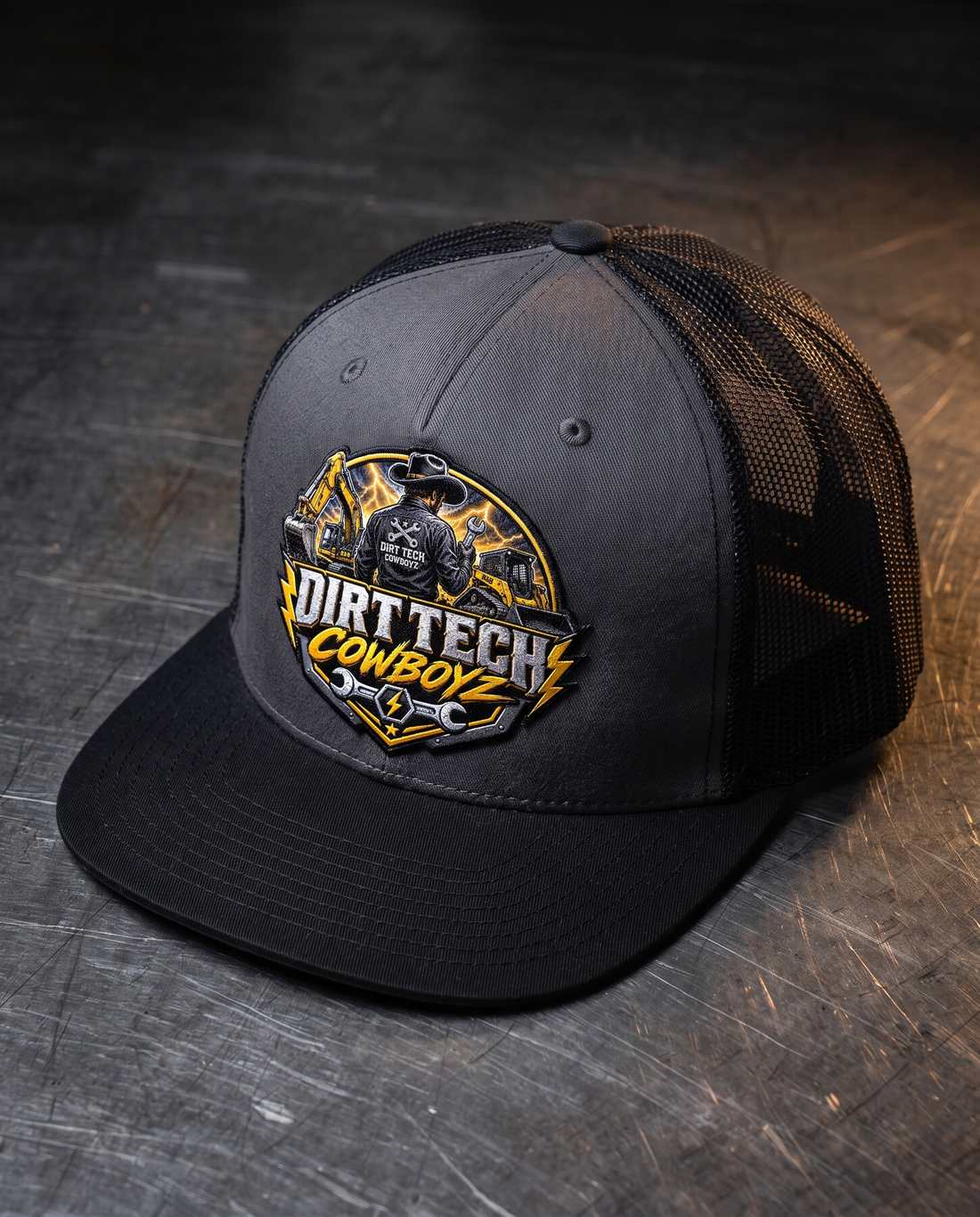 Black and charcoal Dirt Tech Cowboys trucker cap on a steel workbench.